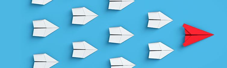 blue wall with white paper airplanes in formation, following a red paper airplane